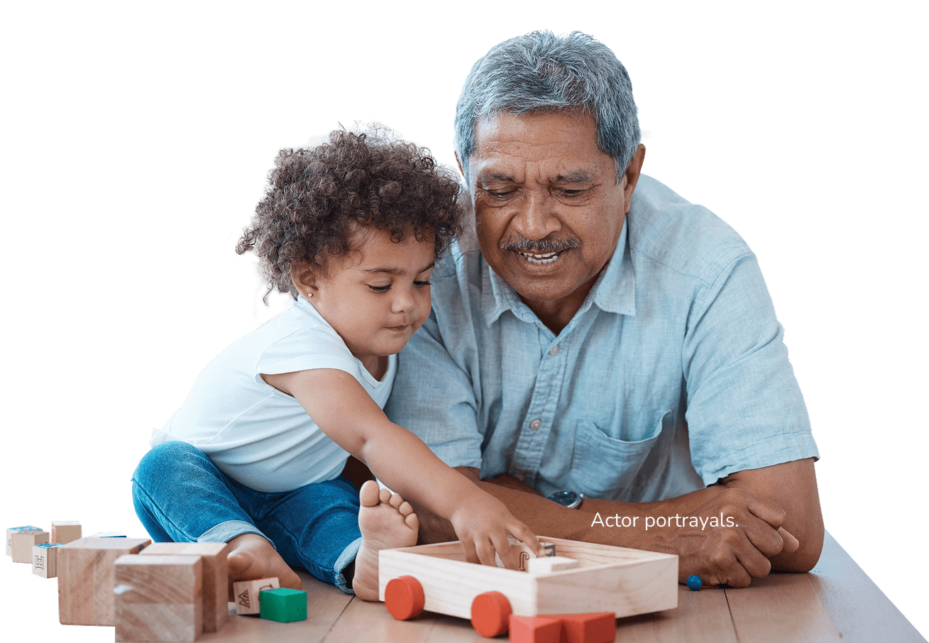 Elderly man with gray hair and a gray mustache in a blue shirt playing with building blocks with a small child with brown hair in a white shirt and jeans